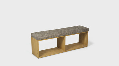 A contemporary ottoman with a grey, upholstered seat and a natural oak frame. 
