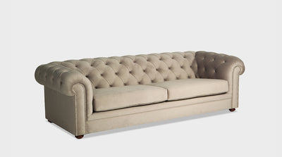 A classic sand coloured Chesterfield sofa with diamond button and stud details. It has ornate natural mahogany legs.