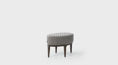 An oval, mid-century ottoman with plush, grey upholstered seat and a timber base with tall, tapered legs.