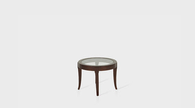 An art deco inspired side table with a glass top and curving, medium mahogany legs.
