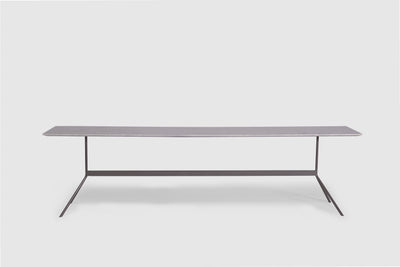 A contemporary sofa table that has a rectangular, marble top and slim, grey, steel legs.