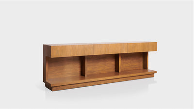 A sleek and modern sofa table made from natural oak. It has a rectangular top, three drawers and three separate shelves below. 