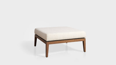 A square, modern ottoman upholstered in white boucle with an oak base and legs.