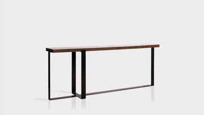 A console table with four intersecting black steel, thin legs and a walnut rectangular top.