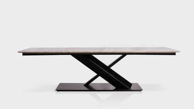 A contemporary dining table with a rectangular, marble top and a black steel, x base. 