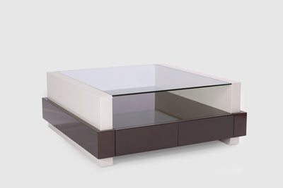 A modern coffee table with a papyrus coloured frame and dark mahogany drawers that have a wraparound detail.