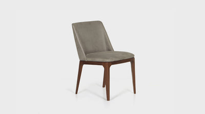 An Italian inspired contemporary dining chair which has a slight wingback, diagonal back legs made of walnut timber and a white cross-stitching detail that lines the tailored oatmeal coloured upholstery.