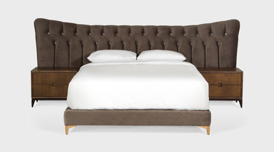 A bed that has a classic design with a brown velvet, diamond button, upholstered headboard and an upholstered bed base that has oak legs. 