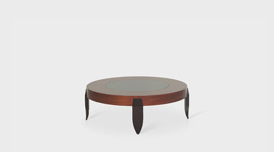 An art-deco inspired, round coffee table with a natural mahogany frame, glass top and dark mahogany tapered legs. 