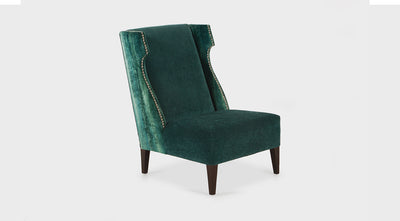 An armless, emerald green occasional chair with a wingback and stud detail. It is fully upholstered with medium mahogany timber legs.