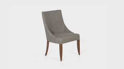 A classic dining chair with a curved frame and natural mahogany legs. It has a white cross-stitching detail that lines the tailored, grey, upholstery and warm brown, leather patches. 