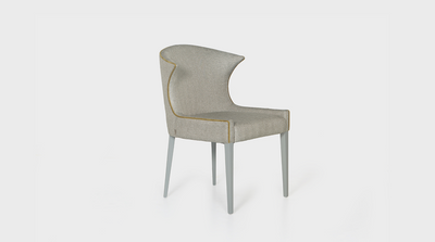 A dining chair that is inspired by classic Scandinavian and Mid-Century design. It has smooth curves and grey coloured, mahogany, tapered legs. It features tailored ecru coloured upholstery and a beautiful mustard coloured piping detail.