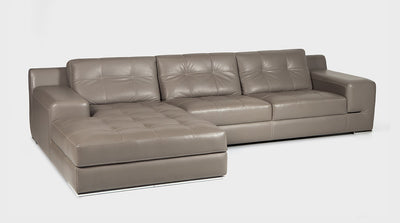 A Stone leather sofa with a chaise and wide arms. The upholstery is enhanced by a white block stitch detail on the cushions and a double stitch detail on the base.