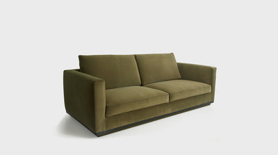 A fully upholstered, olive green sofa that has a modern design with an oak base. 