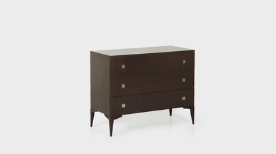 A French inspired chest of drawers with three dark mahogany drawers that have silver handles and slim dark mahogany legs.