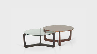 Contemporary, nesting coffee tables with three-legged, crossed bases made of dark and natural mahogany and round tops made of glass and natural mahogany.