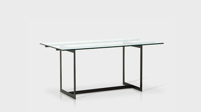 A rectangular dining table that has a sleek and effortless, contemporary design with black, powder coated, steel legs and a clear glass top. 