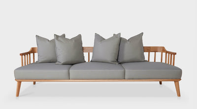 A sofa with a Scandinavian design, featuring a low timber frame, diagonal legs and grey upholstered seats and scatter cushions, front view.