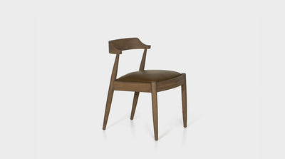 An armless Scandinavian dining chair with an oak timber frame and brown leather upholstered seat.