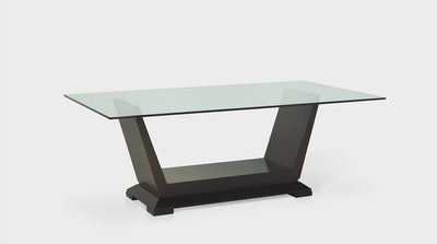 An art deco dining table with a glass top and a solid looking, dark mahogany base with diagonal lines. 