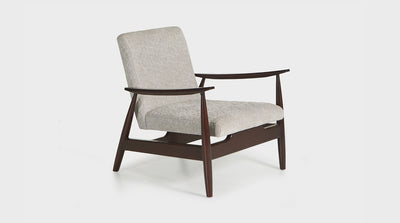 A mid-century inspired occasional chair that has a sculptural frame, curved arms and diagonal legs with a seat that is upholstered in grey quilted fabric.