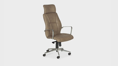 A desk chair with a subtle curved backrest and wingback upholstered in tan leather. It features a headrest, chrome arms and base, with wheels, that is adjustable.