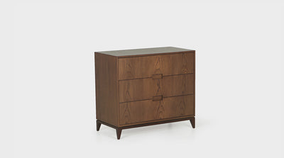 A min-century chest of drawers with three, oak drawers, groove handles and a shadow line detail. It has mahogany, tapered legs. 