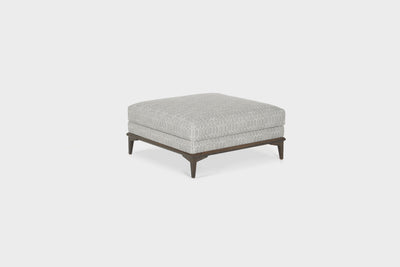 A modern, square, grey, upholstered ottoman with an oak base and legs.