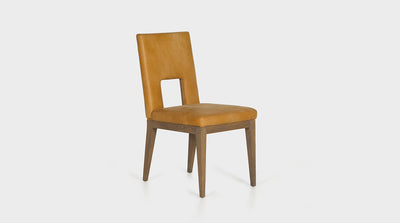 A modern dining chair with a minimalistic silhouette which is offset by the bold, mustard colour of the leather upholstery. It features a square cut out in the chair’s backrest and has oak timber legs.