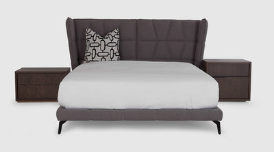 A uniquely designed bed with a fully upholstered headboard that features a xxx detail and an upholstered, fluted bed base that has slim, black, steel legs.