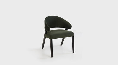 A dining chair with a fully upholstered wraparound back and seat. It features black, timber, diagonal legs.