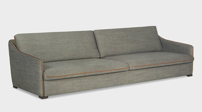 A fully upholstered, grey, contemporary sofa that has orange piping, slim arms and is extra depth.