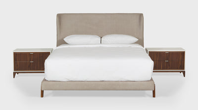A contemporary bed with an upholstered bed base and head board which features a slight wingback. The base has unique, walnut timber legs. 