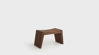 A contemporary stool with a curved seat and diagonal legs made from oak.