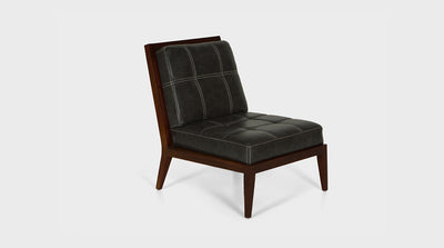 An armless contemporary occasional chair with a walnut frame.  The black leather luxury upholstery on the seat has a white block stitching detail.