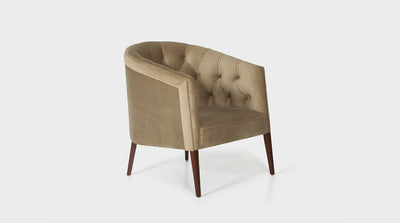 A mid-century inspired occasional chair with a tub shaped design. It has camel coloured velvet diamond button upholstery, a softly curved back and tapered legs made of medium mahogany timber.